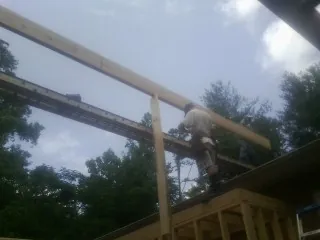Carpenter setting a ridge beam over a new addition frame — Ice Dam Removal by Roofing Brothers in Cabin John