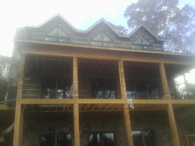 Dormers and porch framing on a large log home under construction — Roof Coating work by our crew in Cabin John