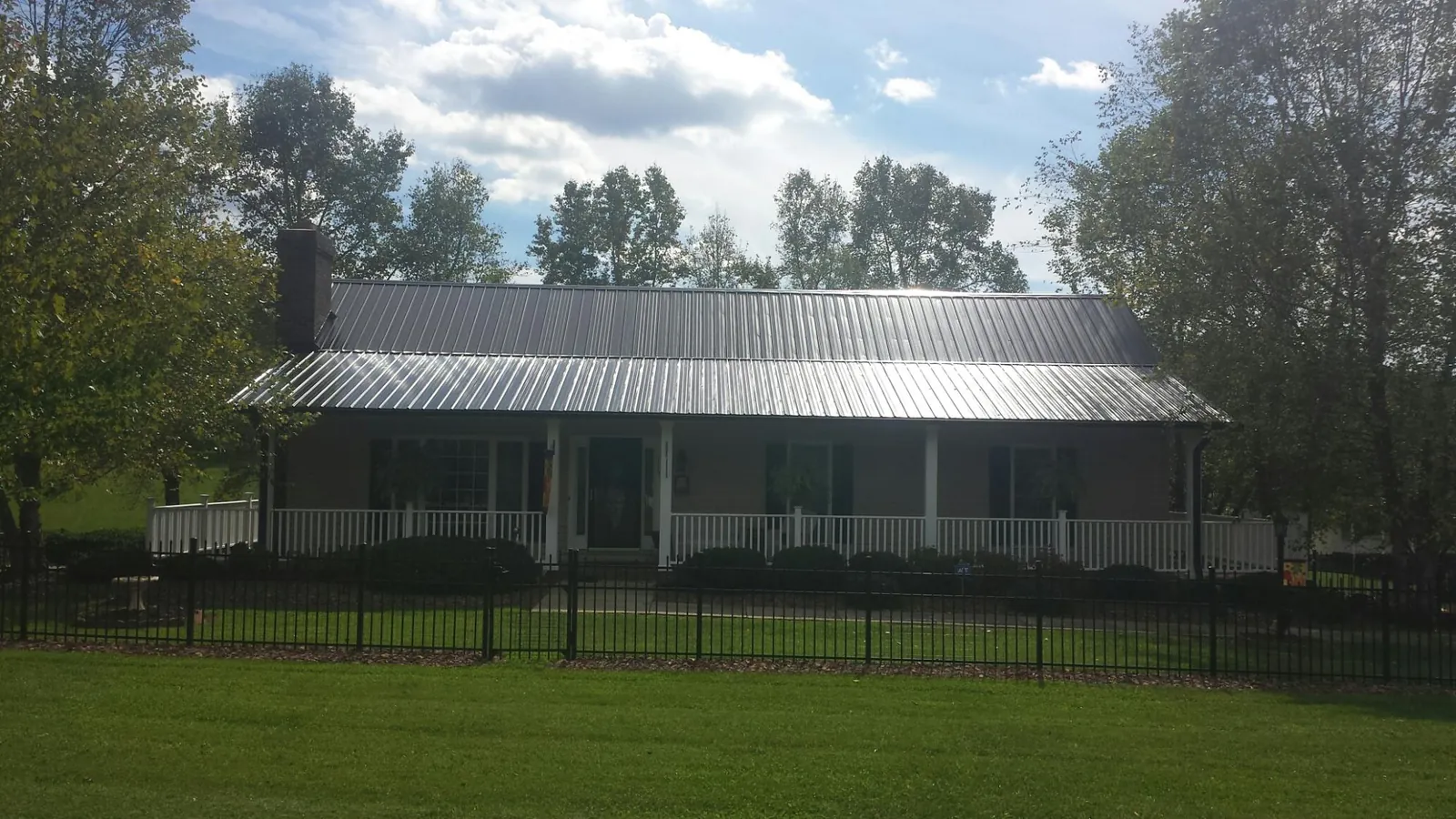 Gray metal roof on a brick ranch with a full width front porch — Gutter Guard Installation work by our crew in Cabin John