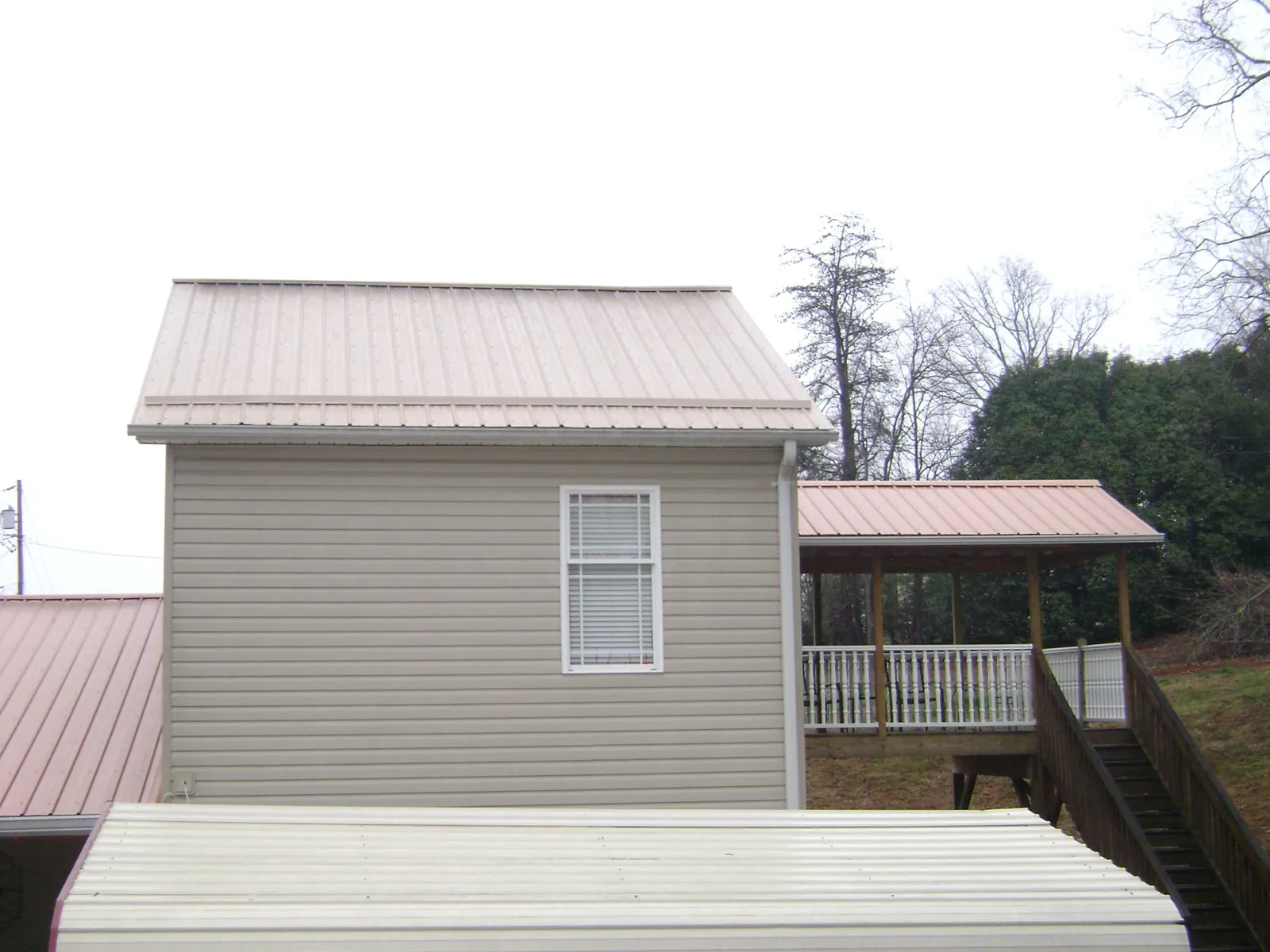 Tan metal roofs on a two story addition and attached porch, from a Roof Replacement job in Cabin John
