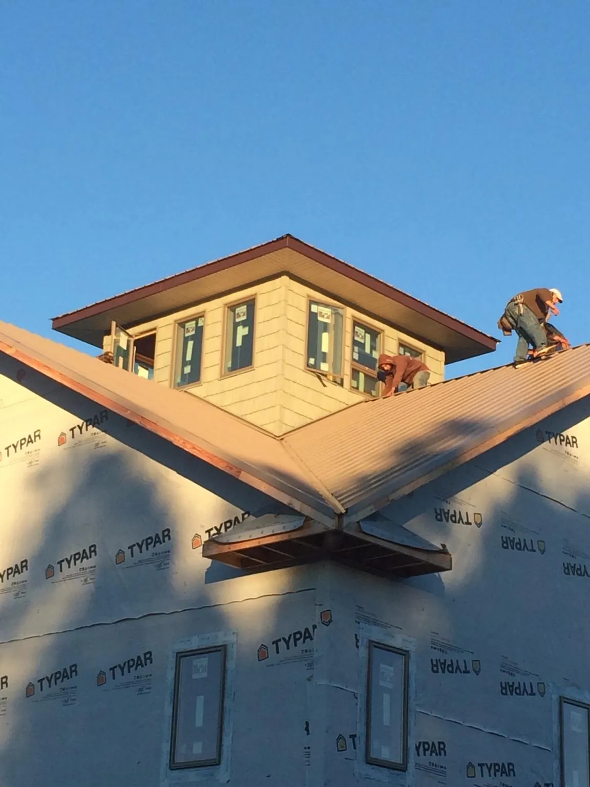 Roofers working around a rooftop cupola on a new metal roof at sunset — Roof Waterproofing in Cabin John by Roofing Brothers